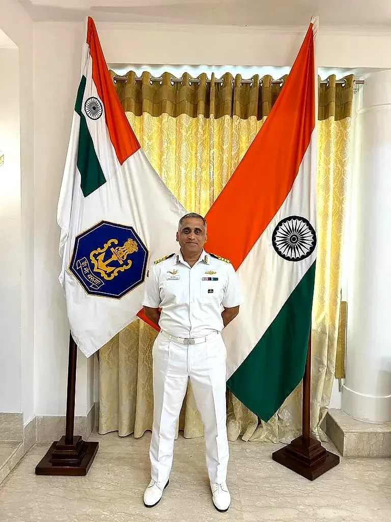 Captain Mahesh Khochare (Retd.) in Navy dress whites, the Naval ensign and the tricolour behind him