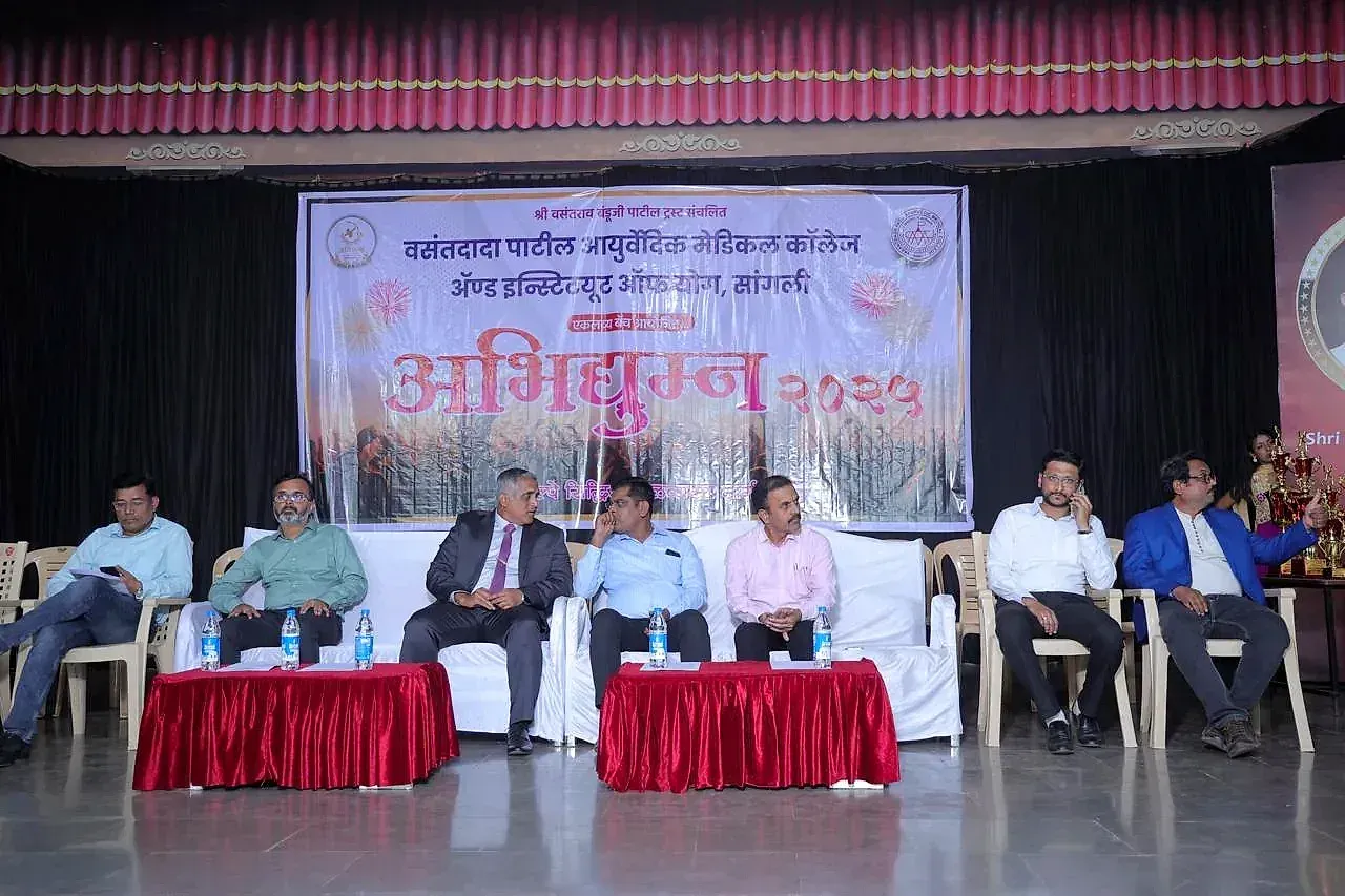 A seated panel of guests on stage at a school event