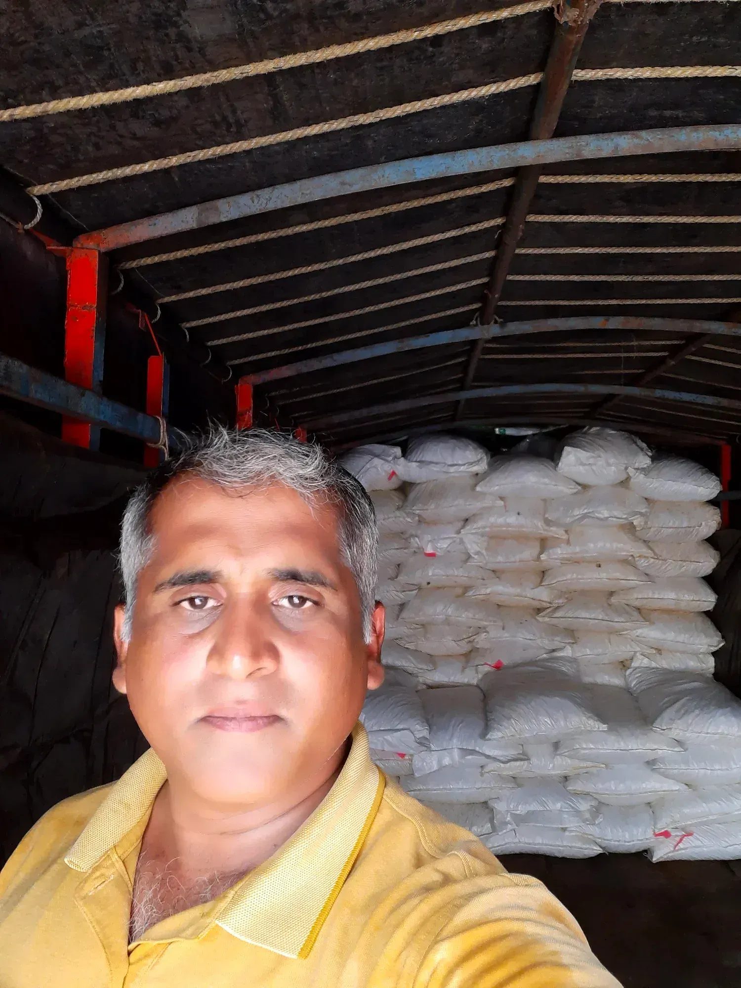 A man beside white sacks stacked high inside a covered truck