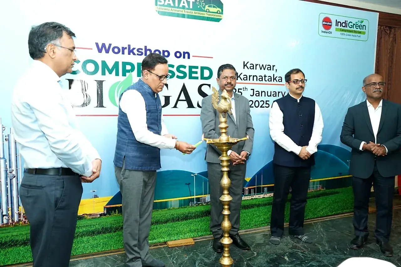 Four men standing beside a Compressed Biogas workshop banner at Karwar